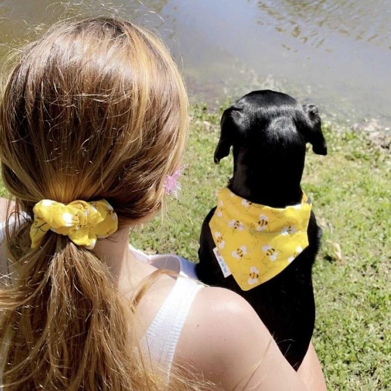 Dog wearing the Buzzin' with Betty bandana, showcasing a yellow background with floating bees matching the humans Buzzin' with Betty scrunchie.