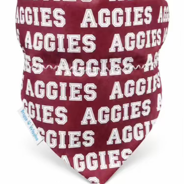 A dog bandana featuring a maroon background with a repeating white 'AGGIES' text pattern, shown on a plain white background.