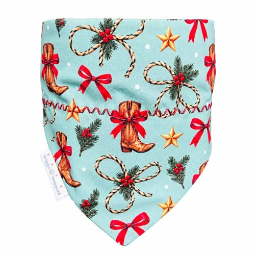 Aqua western Christmas dog bandana with cowboy boots, rope bows, red ribbons, gold stars, and festive greenery on a white background.