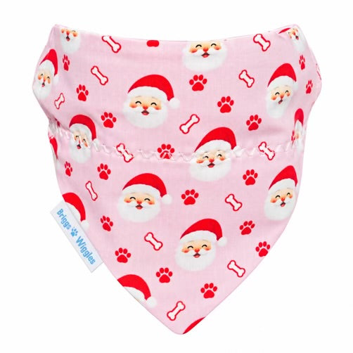 Pink Christmas dog bandana featuring Santa faces, red paw prints, and outlined dog bones, with a Briggs ’n’ Wiggles label on a white background.